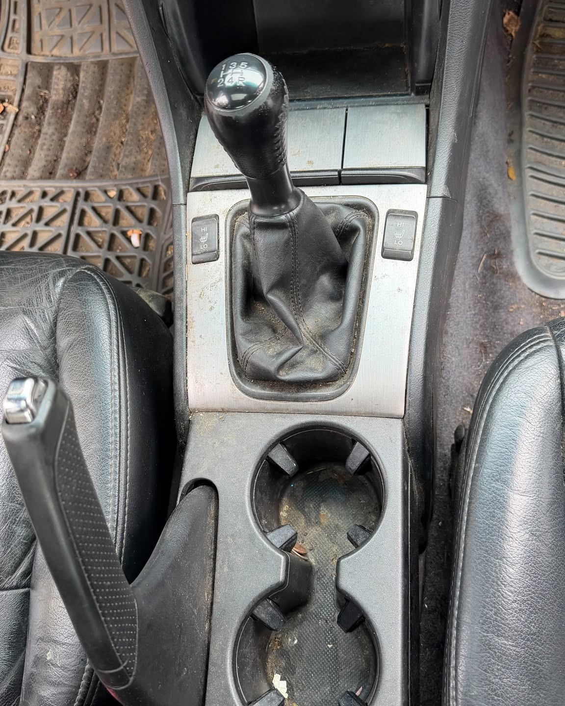 Centre console and cupholders full of grime and debris before detailing