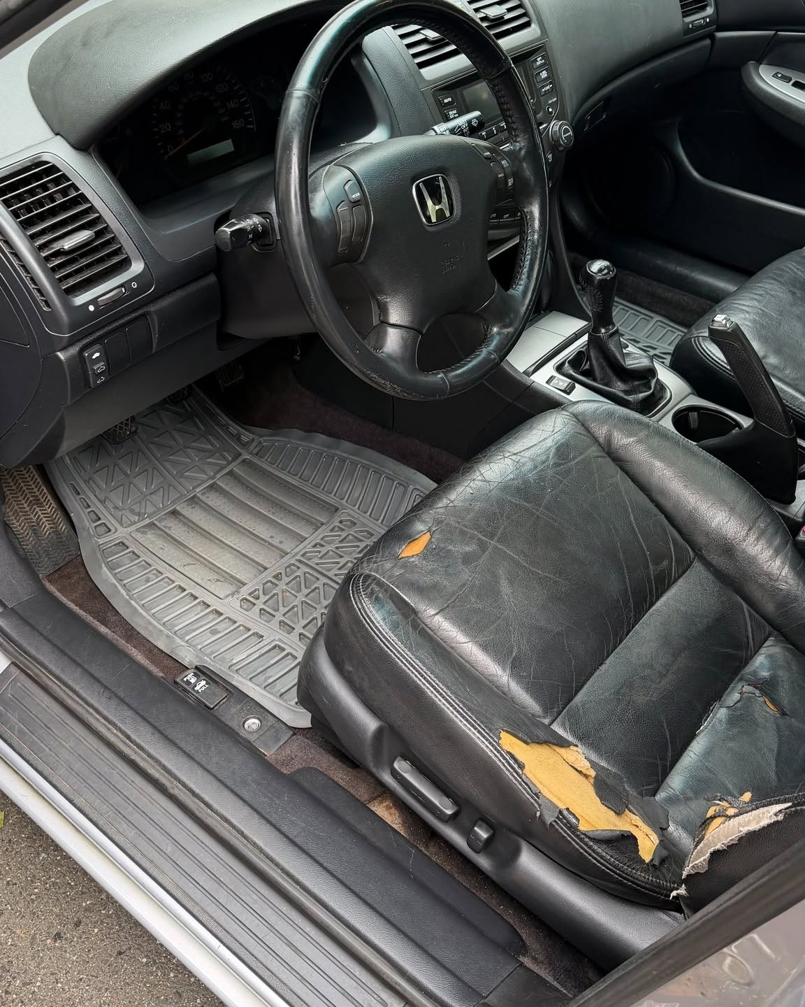 Driver side interior with worn leather seat before detailing